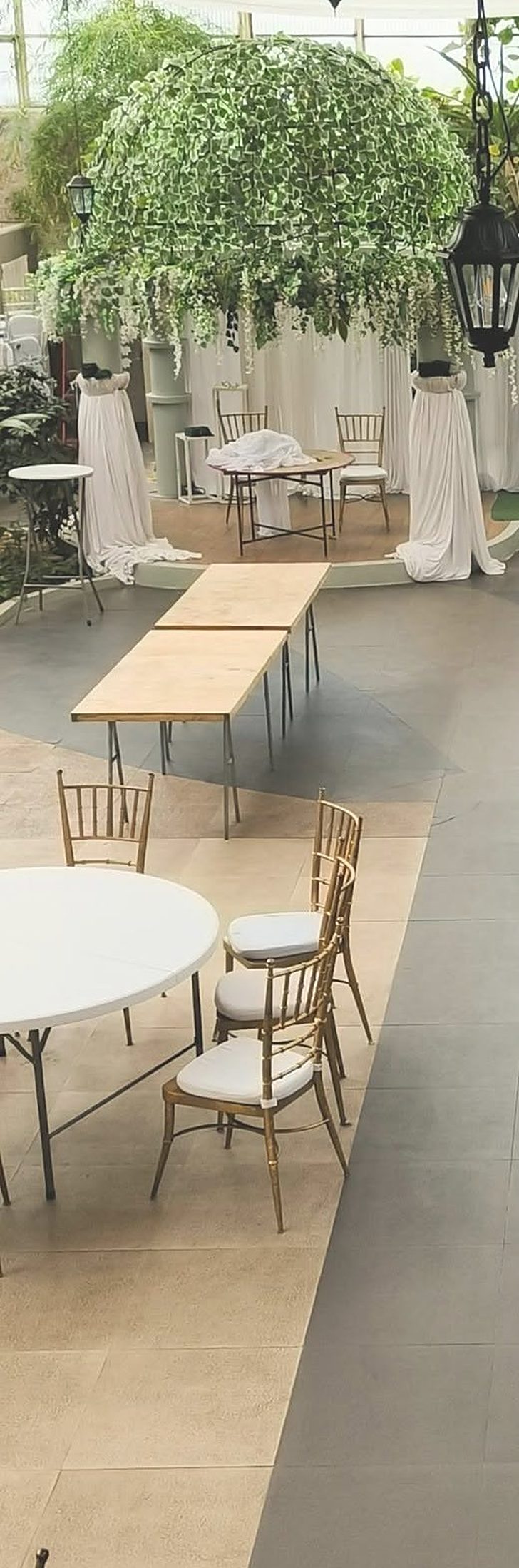 Salón de eventos con domo de follaje, faroles y columnas con tela blanca para una boda