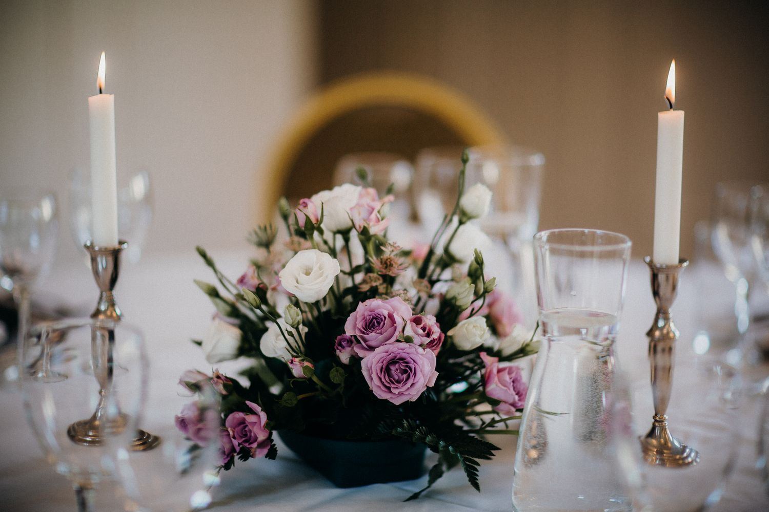 Centro de mesa con flores rosas y velas altas en una recepción elegante