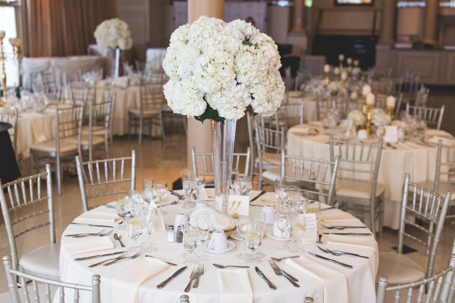 Mesas redondas con arreglos florales y mantelería blanca listas para un evento